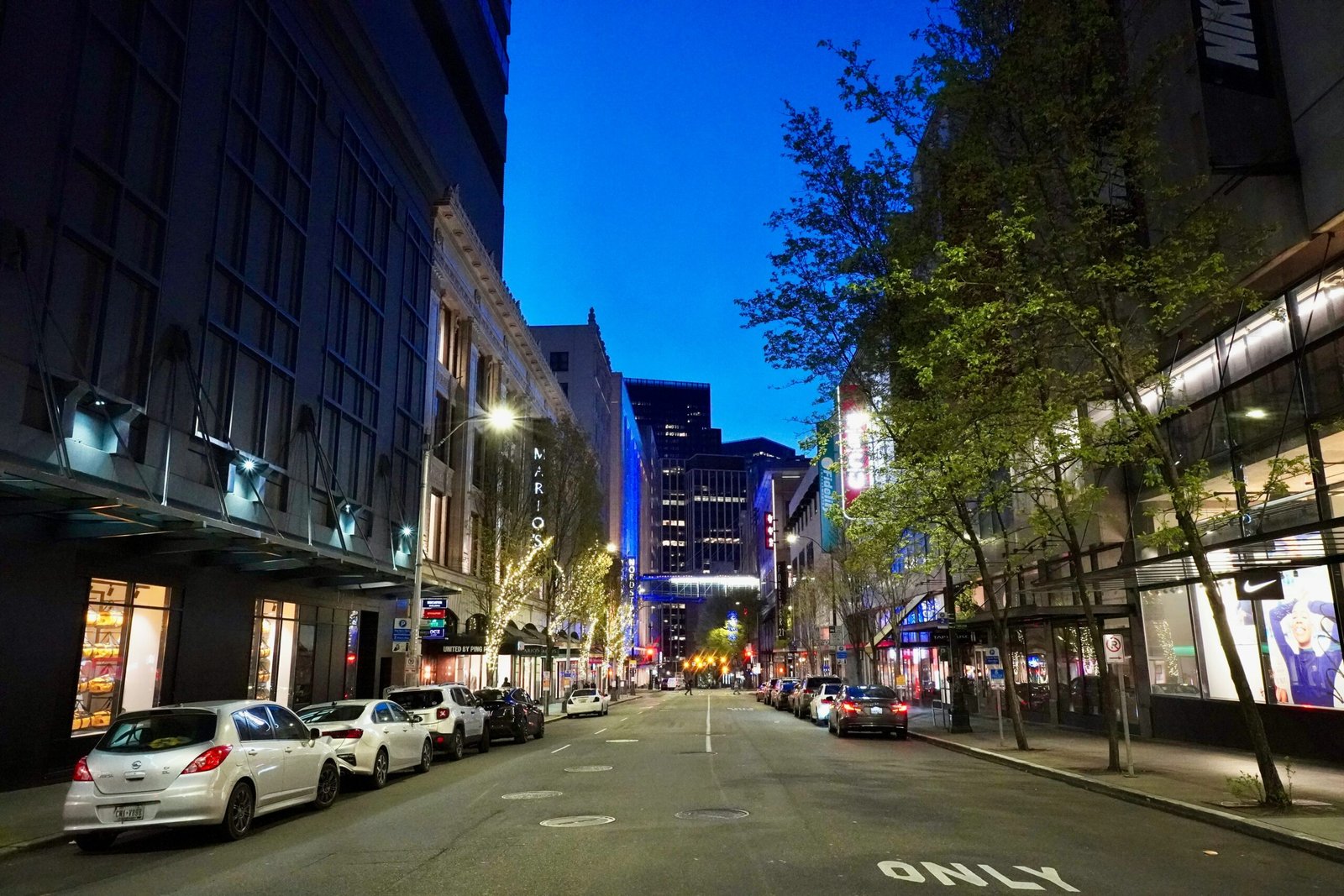 a city street at night with cars parked on both sides